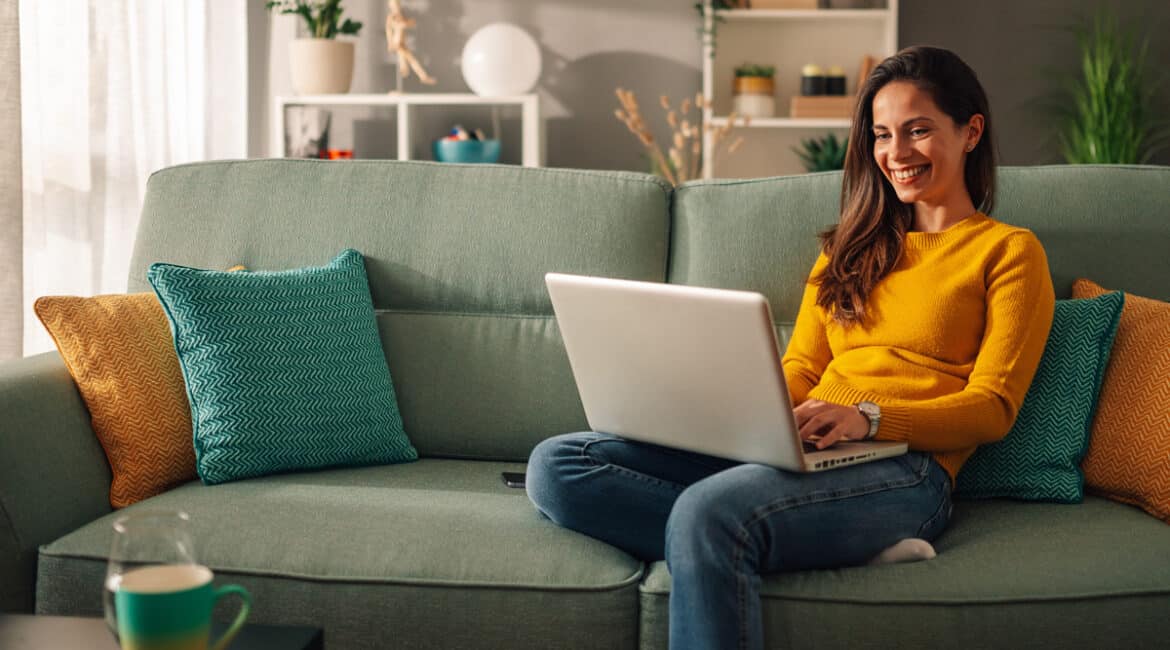 woman on couch using-internet on a laptop